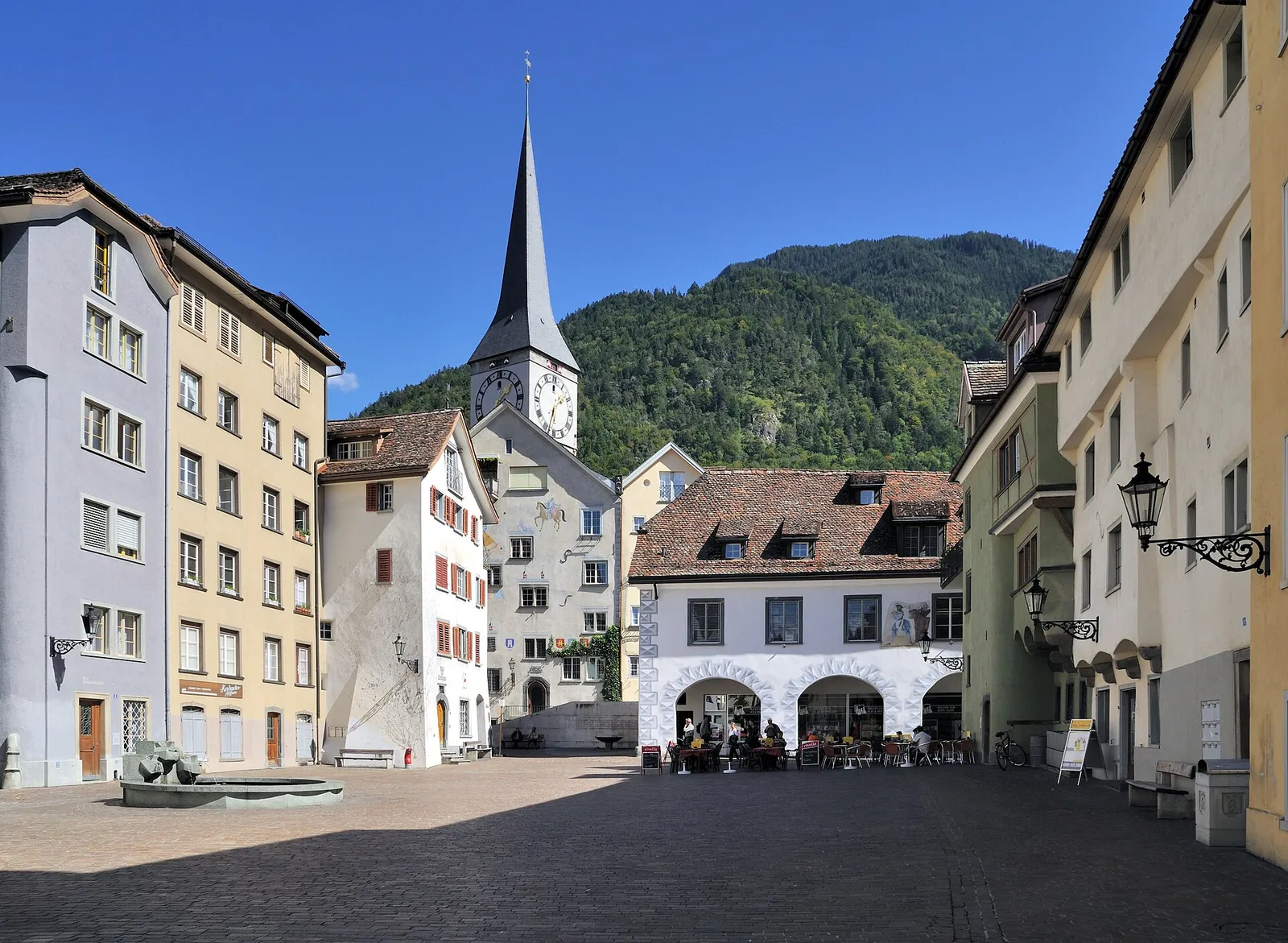Coira: piazza del centro storico con un campanile e le montagne sullo sfondo